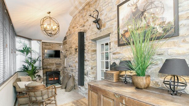 A stone-walled room with a fireplace, wooden furniture, and a large potted plant. - 3 bedroom accommodation in Barley, near Barrowford (Barley, near Barrowford)