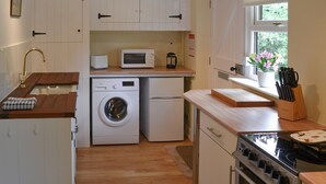 A compact kitchen with a washing machine, microwave, and stove. - Broad Cottage Boathouse (Ranworth, near Wroxham)