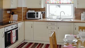 A modern kitchen with white cabinets, a microwave, an oven, a sink, and a dining area with a table set for two.