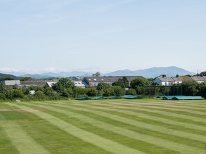 A grassy field with a row of houses and a mountain range in the background. - 3 bedroom accommodation in Haverigg, near Millom (Haverigg, near Millom)