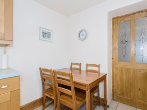 A dining area with a wooden table and chairs, a clock, and a framed picture on the wall.