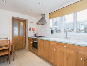 A kitchen with wooden cabinets, a gas stove, a sink, and a window with a view. - 3 bedroom accommodation in Haverigg, near Millom (Haverigg, near Millom)