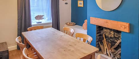 A dining room with a wooden table and chairs, a fireplace, and a blue accent wall.
