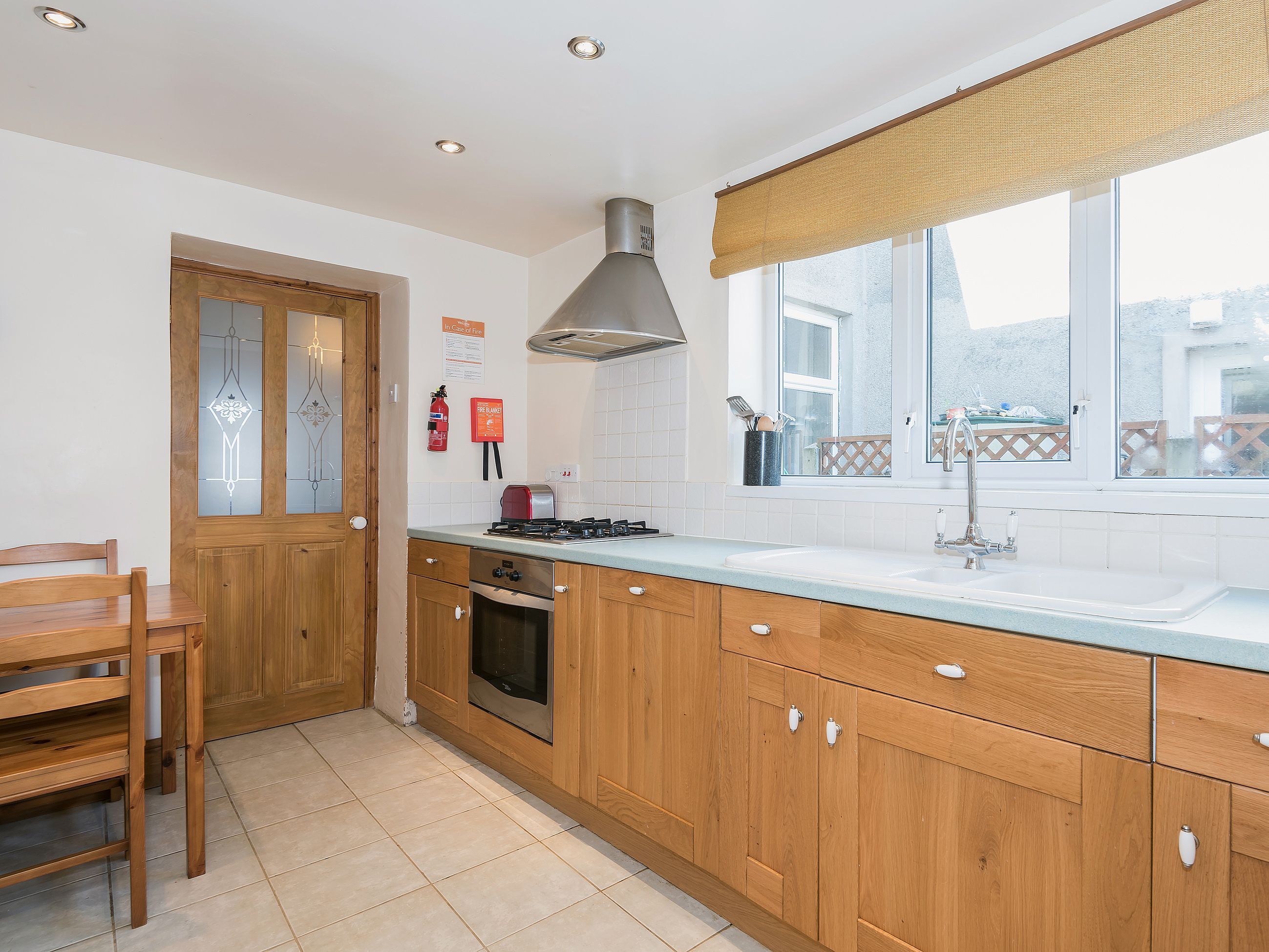 A kitchen with wooden cabinets, a gas stove, a sink, and a window with a view.