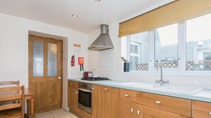 Una cocina con armarios de madera, una estufa a gas, un lavabo y una ventana con vistas.