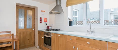 Una cocina con armarios de madera, una estufa a gas, un lavabo y una ventana con vistas.