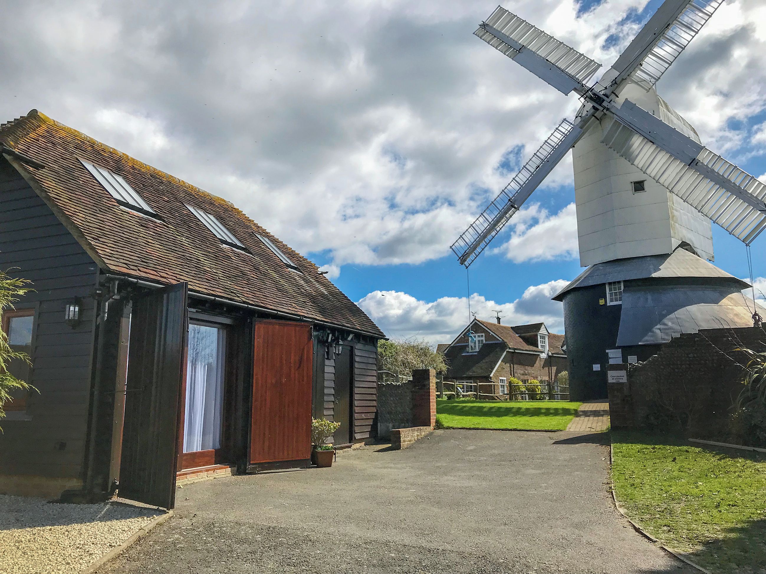 A traditional windmill and a rustic building with a gravel path leading to it.