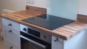 A kitchen with a built-in induction cooktop, a stainless steel oven, and wooden countertops. - 3 bedroom accommodation in Bakewell (Bakewell)