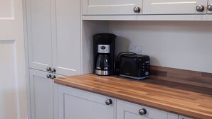 A kitchen with white cabinets, a wooden countertop, a coffee maker, and a toaster. - 3 bedroom accommodation in Bakewell (Bakewell)