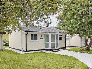 A small, single-story building with a white exterior and black trim. It has a covered porch with a glass door and windows, and a sign that reads "STAFFORD".