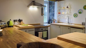 Una cocina moderna con encimeras de madera, lavavajillas Bosch y una pared de piedra.