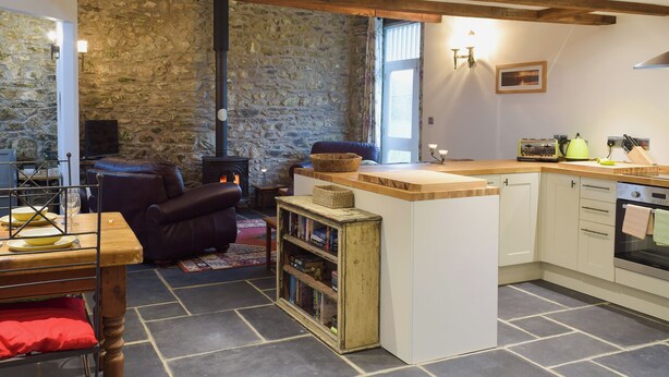 Una sala de estar acogedora con una pared de piedra, chimenea, sofá de cuero y mesa de centro de madera.