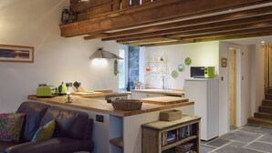 Una cocina acogedora con vigas de madera, un comedor con un sofá de cuero marrón y una estantería.