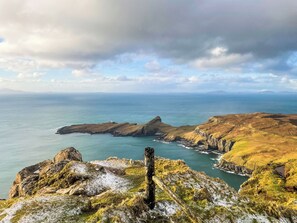 A coastal landscape with rocky terrain, a lighthouse, and a clear view of the sea.