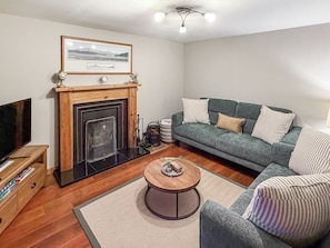 A living room with a fireplace, a sofa, a coffee table, and a television.