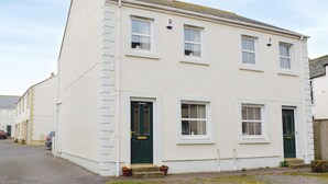 A two-story building with a white facade, multiple windows, and a green door. - 2 bedroom accommodation in Allonby, near Maryport (Allonby, near Maryport)
