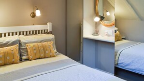 A bedroom with a bed, pillows, a nightstand, a lamp, and a mirror.