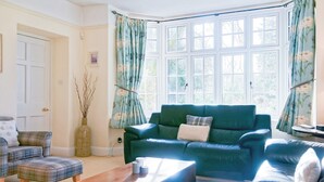 A living room with a green sofa, a plaid armchair, and a wooden coffee table. - 3 bedroom accommodation in Bowness-on-Windermere, near Windermere (Bowness-on-Windermere, near Windermere)