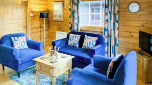 A cozy room with a blue sofa set, a wooden coffee table, and a clock on the wall. - 2 bedroom accommodation in Banavie, near Fort William (Banavie, near Fort William)
