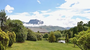 A house with a sloped roof surrounded by lush greenery and a clear sky. - 2 bedroom accommodation in Banavie, near Fort William (Banavie, near Fort William)