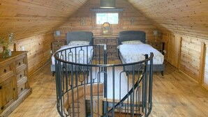 A cozy attic bedroom with two beds, a spiral staircase, wooden walls, and a large window. - 2 bedroom accommodation in Banavie, near Fort William (Banavie, near Fort William)