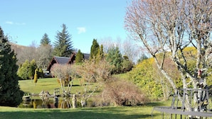 A serene outdoor setting with a pond, a wooden cabin, and a metal fence. - 2 bedroom accommodation in Banavie, near Fort William (Banavie, near Fort William)