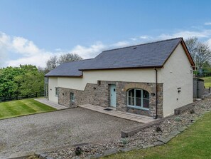 A single-story house with a stone facade, a pitched roof, and a gravel driveway.