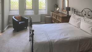 Une chambre à coucher comprenant un lit, une chaise, une commode, un miroir et un radiateur.
