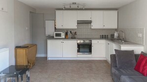 Une cuisine de taille réduite avec des meubles blancs, un four à micro-ondes, un four traditionnel et un évier.