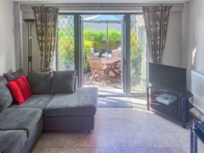 Ein Wohnzimmer mit Sofa, Fernseher und einer Glasschiebetür zu einer Außenpatio.
