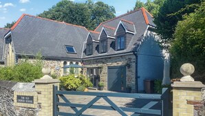 Un bâtiment traditionnel en pierre, doté d’un toit sombre, d’une entrée fermée par un portail et d’une enseigne indiquant : « The Old Church School ».