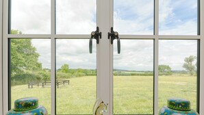 A window with a view of a grassy field, two vases on the windowsill, and a lock on the window. - The Calf Shed-UKC2113 (Royal Wootton Bassett)