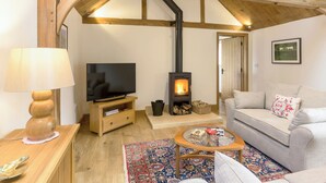 A cozy living room with a TV, a fireplace, a sofa, and a wooden ceiling. - The Calf Shed-UKC2113 (Royal Wootton Bassett)