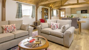 A spacious living area with two sofas, a glass coffee table, and a wooden ceiling. - The Calf Shed-UKC2113 (Royal Wootton Bassett)