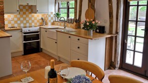 A kitchen with a dining area, featuring a stove, oven, sink, and a table set for dining.