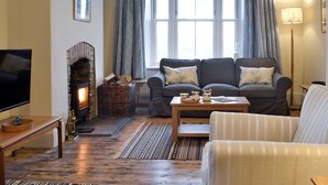 A cozy living room with a fireplace, a sofa, a coffee table, and a television. - 4 bedroom accommodation in Capel Bangor, near Aberystwyth (Capel Bangor, near Aberystwyth)