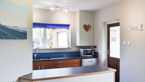 Een moderne keuken met een ingebouwde magnetron, een spoelbak en een raam met blauwe luiken.