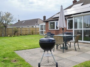 Ein Garten mit Grill, Gartenmöbeln und einer Patio-Terrasse.