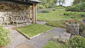 A stone building with a bench outside, surrounded by a well-maintained garden and a stone wall. - Gardener's Cottage-UXT (Near Castle Douglas)