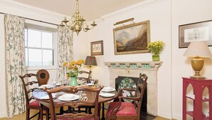 A dining room with a fireplace, a chandelier, and a table set for four. - Gardener's Cottage-UXT (Near Castle Douglas)