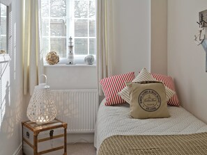 A bedroom with a bed, striped pillows, a decorative pillow, a small table with a lamp, and a window with blinds. - 3 bedroom accommodation in Foxholes, near Scarborough (Foxholes, near Scarborough)