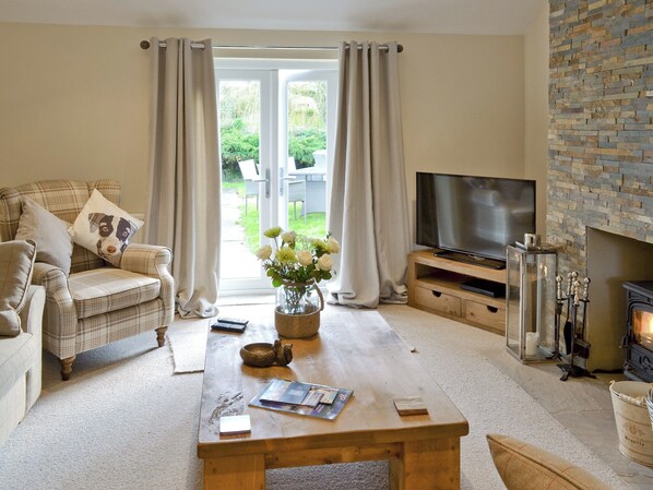 A living room with a sofa, a coffee table, a TV, and a fireplace. - 3 bedroom accommodation in Foxholes, near Scarborough (Foxholes, near Scarborough)