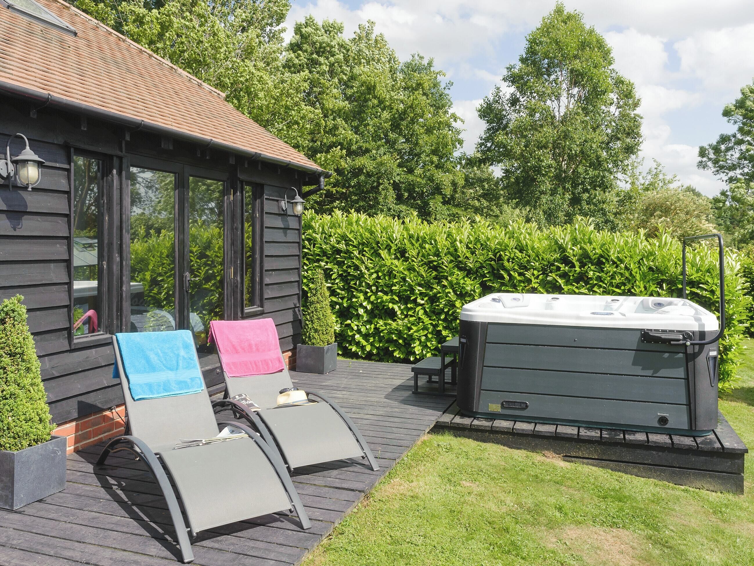A wooden deck with two lounge chairs and a hot tub.