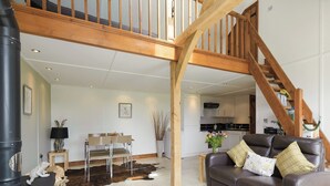 A spacious living room with a high wooden ceiling, a fireplace, a sofa, and a dining area. - 1 bedroom accommodation in White Colne, near Colchester (White Colne, near Colchester)