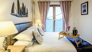 A hotel room with a bed, a bedside table with a lamp, a tray with breakfast items, and a view of the outside. - 4 bedroom accommodation in Wells-next-the-Sea (Wells-next-the-Sea)