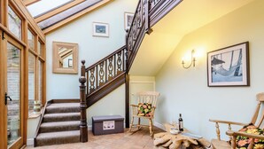 A staircase with wooden railings, a wooden bench, and a table with a woven base. - 4 bedroom accommodation in Wells-next-the-Sea (Wells-next-the-Sea)