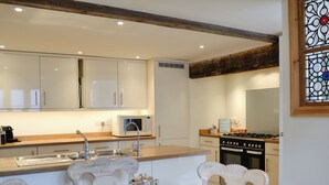 A modern kitchen with white cabinets, a microwave, a stove, and a dining area with a table set for two. - 3 bedroom accommodation in Chulmleigh, near South Molton (Chulmleigh, near South Molton)