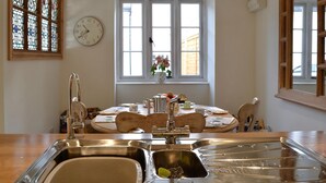 A kitchen with a double sink, a clock, and a window with a view of the outside. - 3 bedroom accommodation in Chulmleigh, near South Molton (Chulmleigh, near South Molton)