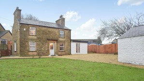 A stone house with a front door, two windows, and a small front yard.