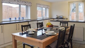 A kitchen with a dining table set for four, a microwave, and a kettle.